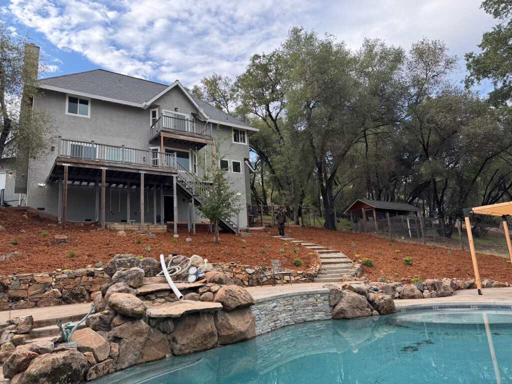 Real project: backyard landscape with stone pool surround, fresh mulch, and new plantings